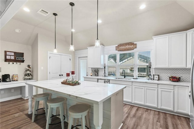 4019 Heru Ct, College Station, TX 77845 - kitchen featuring wood finished floors, lofted ceiling, tasteful backsplash, white cabinets, and a center island