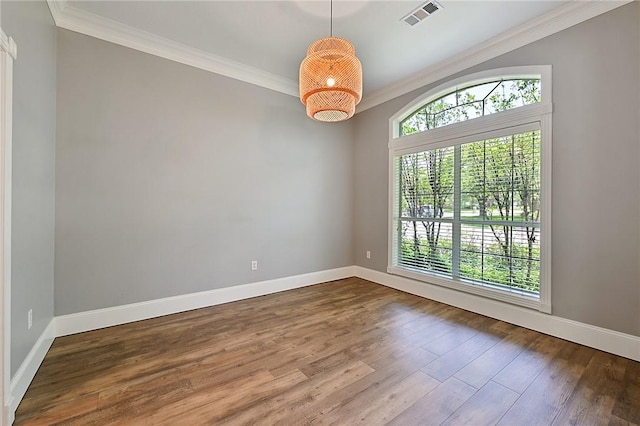 empty room with crown molding, baseboards, and wood finished floors
