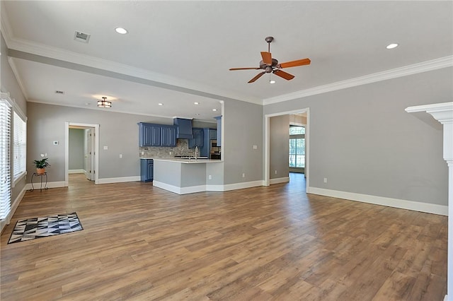 unfurnished living room with a ceiling fan, wood finished floors, recessed lighting, crown molding, and a sink