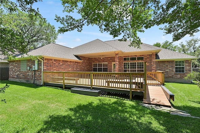 back of property featuring brick siding, roof with shingles, and a lawn