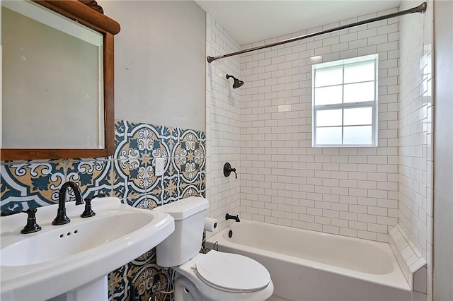 full bath with a sink, toilet, tub / shower combination, and tile walls
