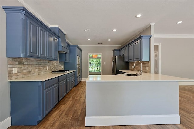 kitchen with freestanding refrigerator, a sink, a peninsula, ornamental molding, and tasteful backsplash