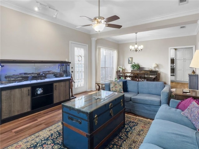 living area with track lighting, ceiling fan with notable chandelier, ornamental molding, and wood finished floors