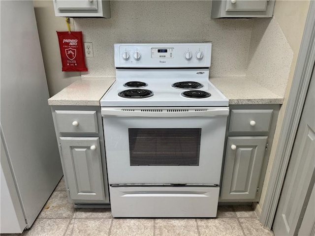 400 Nagle St Unit 304, College Station, TX 77840 - kitchen with white range with electric cooktop, gray cabinets, light tile patterned flooring, and freestanding refrigerator