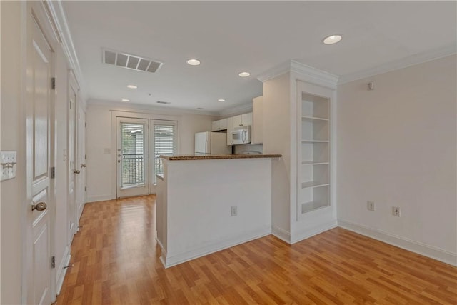 kitchen with white appliances, ornamental molding, kitchen peninsula, and white cabinets