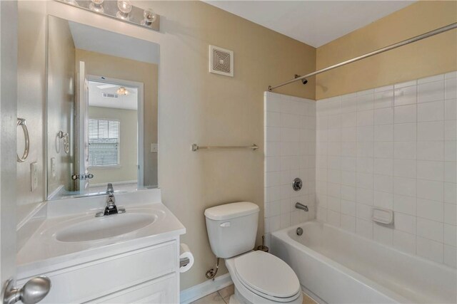 full bathroom featuring tile patterned flooring, vanity, tiled shower / bath, and toilet