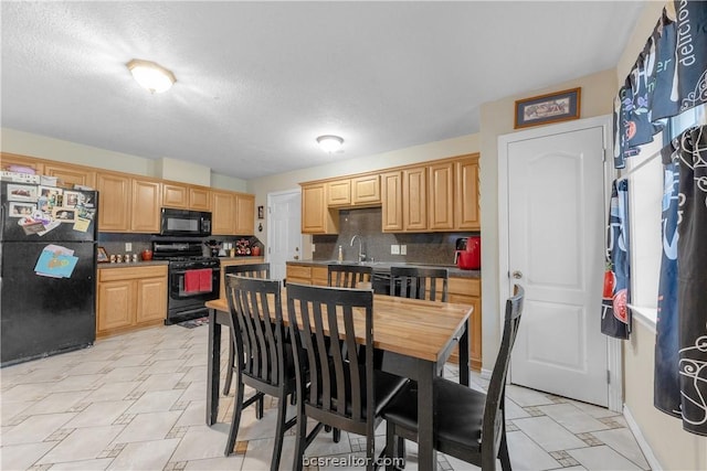 kitchen featuring black appliances, decorative backsplash, light brown cabinets, and a textured ceiling