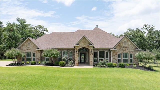 4018 Arboleda Dr, College Station, TX 77845 - french country home featuring stone siding, a front lawn, and roof with shingles