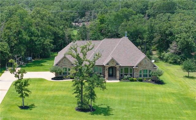 4018 Arboleda Dr, College Station, TX 77845 - view of front of house with stone siding, a front yard, a forest view, and concrete driveway