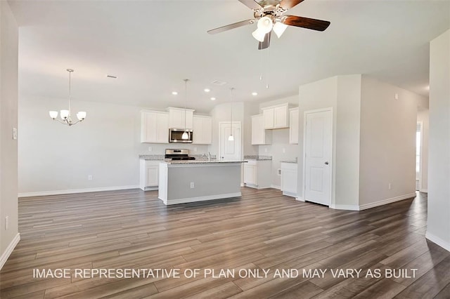 kitchen featuring wood-type flooring, appliances with stainless steel finishes, hanging light fixtures, an island with sink, and white cabinets