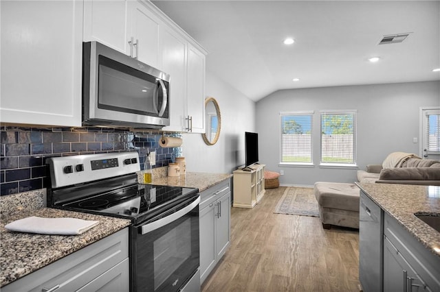 1147 Buffalograss Trl, Sealy, TX 77474 - kitchen with appliances with stainless steel finishes, open floor plan, vaulted ceiling, light wood-type flooring, and backsplash