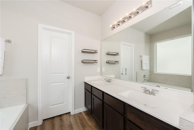 5759 Cerrillos Dr, Bryan, TX 77807 - full bath with wood finished floors, a garden tub, double vanity, and baseboards