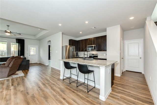 5759 Cerrillos Dr, Bryan, TX 77807 - kitchen with stainless steel appliances, baseboards, dark brown cabinetry, a breakfast bar area, and arched walkways