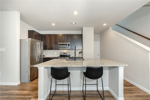 5759 Cerrillos Dr, Bryan, TX 77807 - kitchen featuring stainless steel appliances, a sink, dark brown cabinetry, a kitchen bar, and decorative backsplash