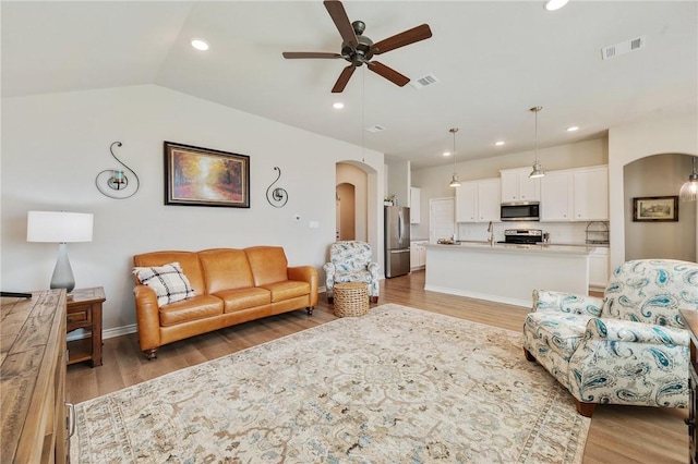 living room featuring ceiling fan, lofted ceiling, sink, and light hardwood / wood-style floors