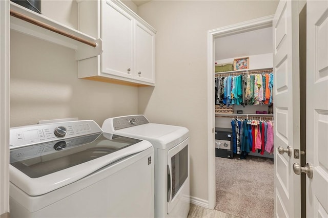 washroom featuring light colored carpet, washing machine and dryer, and cabinets