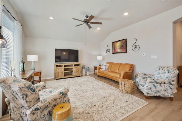 living room with ceiling fan, vaulted ceiling, and light wood-type flooring