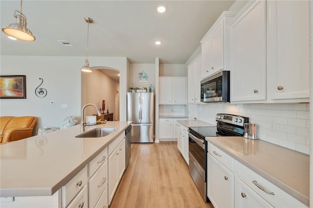 kitchen with appliances with stainless steel finishes, pendant lighting, white cabinetry, an island with sink, and sink