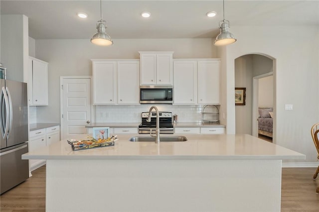 kitchen with a kitchen island with sink, decorative light fixtures, and appliances with stainless steel finishes