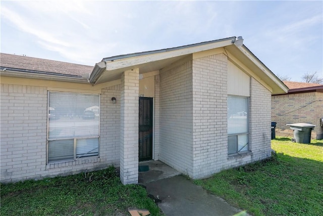 doorway to property featuring brick siding and a yard