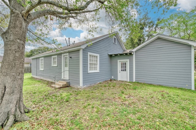 back of property featuring a lawn and entry steps