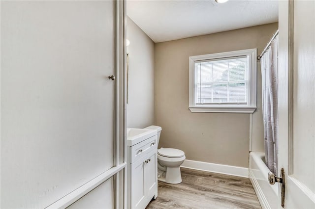 full bath with baseboards, wood finished floors, toilet, vanity, and shower / tub combo