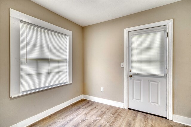 doorway to outside featuring baseboards and light wood-style flooring