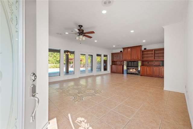 unfurnished living room featuring light tile patterned floors, ceiling fan, and crown molding