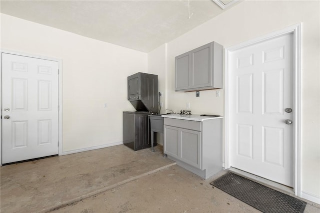 kitchen featuring gray cabinets and stacked washer / dryer