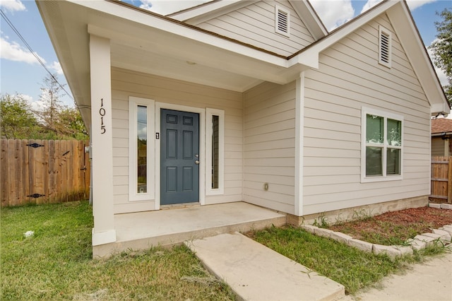 doorway to property featuring a porch and a lawn