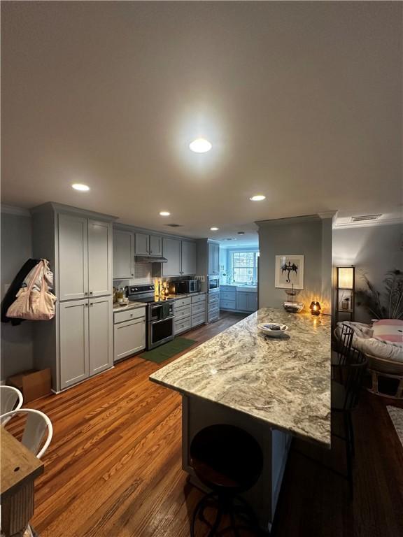 306 Timber St, College Station, TX 77840 - kitchen with appliances with stainless steel finishes, a peninsula, crown molding, a breakfast bar area, and recessed lighting