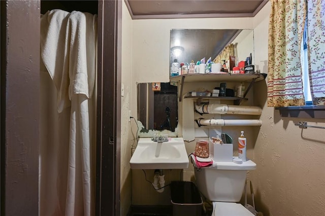 bathroom with a textured wall, a sink, and toilet