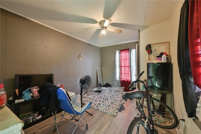 bedroom featuring ceiling fan, crown molding, a textured ceiling, and wood finished floors