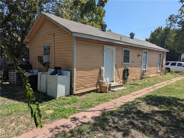 rear view of property featuring washing machine and dryer and a lawn