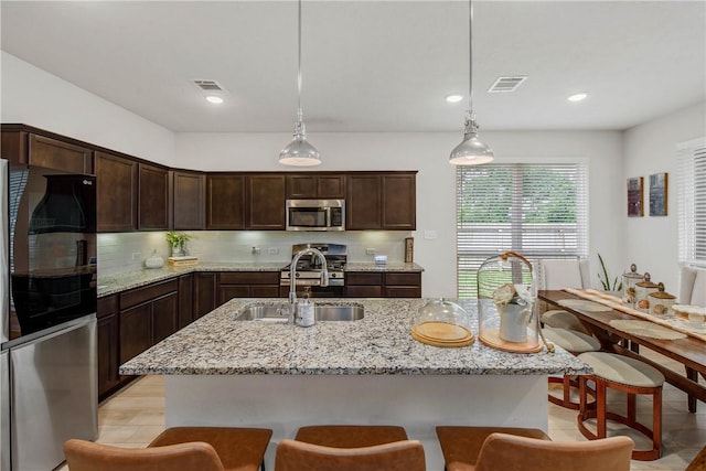 kitchen featuring visible vents, pendant lighting, dark brown cabinetry, a sink, and stainless steel appliances