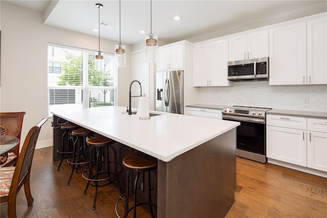 293 Estates Cir, College Station, TX 77840 - kitchen featuring appliances with stainless steel finishes, a sink, an island with sink, a kitchen bar, and backsplash