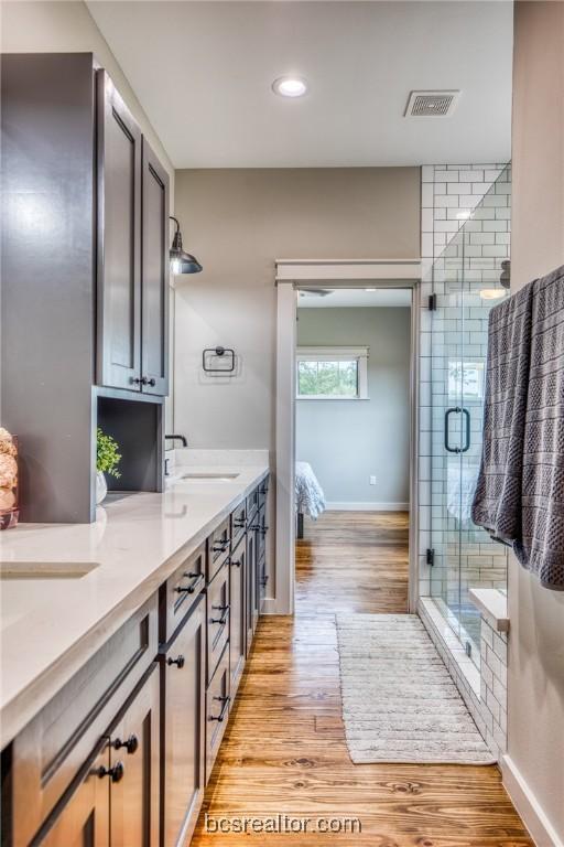 bathroom featuring hardwood / wood-style flooring, vanity, and a shower with door