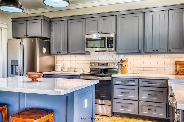 kitchen with backsplash, a kitchen breakfast bar, light hardwood / wood-style floors, appliances with stainless steel finishes, and a kitchen island