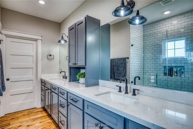 bathroom with vanity, a shower with shower door, and wood-type flooring