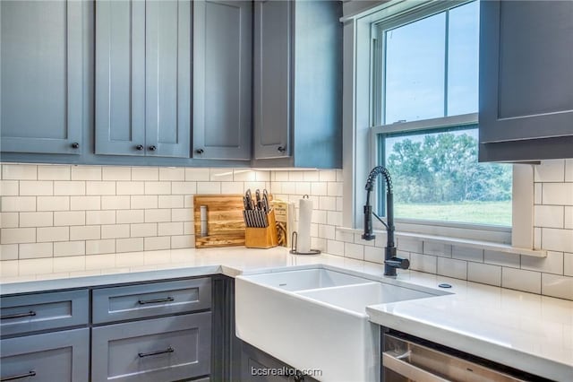 kitchen with gray cabinets, tasteful backsplash, stainless steel dishwasher, and sink