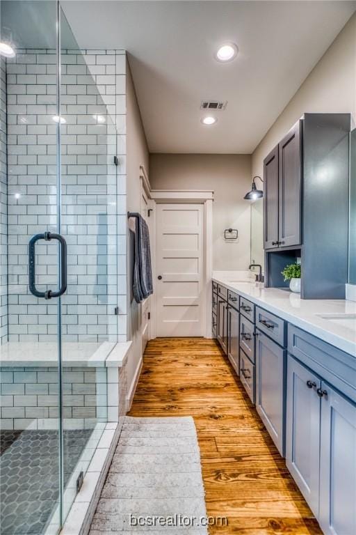 bathroom featuring vanity, an enclosed shower, and wood-type flooring