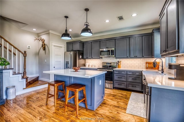 kitchen featuring pendant lighting, a center island, sink, light wood-type flooring, and stainless steel appliances