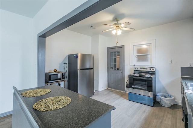 kitchen featuring ceiling fan, stainless steel appliances, and light hardwood / wood-style flooring