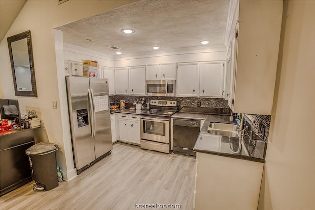 kitchen featuring backsplash, a textured ceiling, stainless steel appliances, sink, and white cabinetry