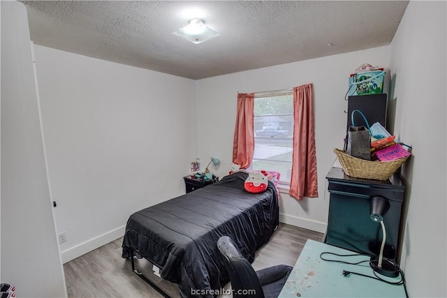 bedroom with a textured ceiling and light wood-type flooring