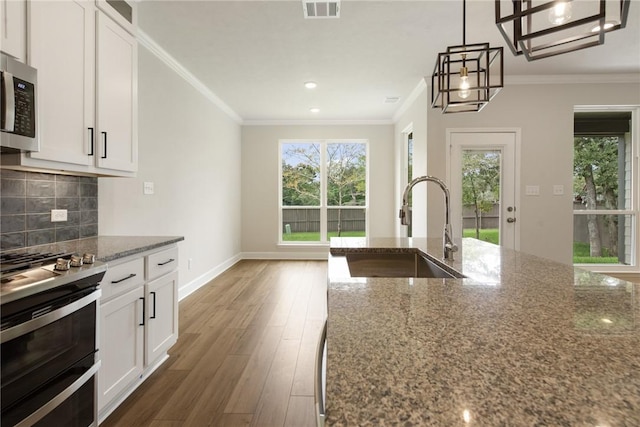 kitchen with light stone countertops, sink, stainless steel appliances, and hardwood / wood-style flooring