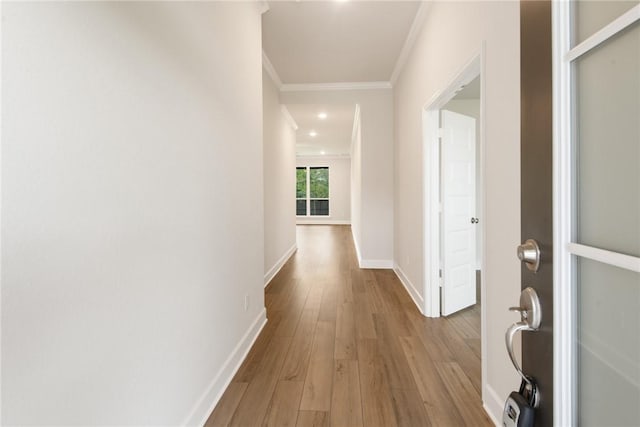 corridor with light wood-type flooring and ornamental molding