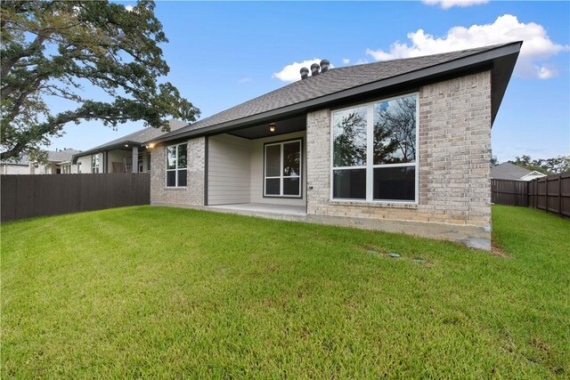 rear view of house with a lawn and a patio