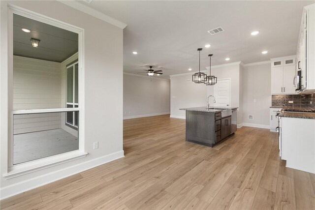 kitchen featuring light wood-type flooring, tasteful backsplash, ceiling fan, white cabinetry, and hanging light fixtures