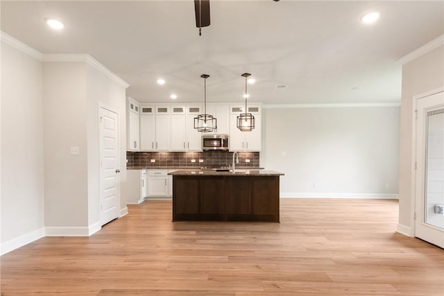 kitchen with white cabinetry, crown molding, hanging light fixtures, and light hardwood / wood-style floors